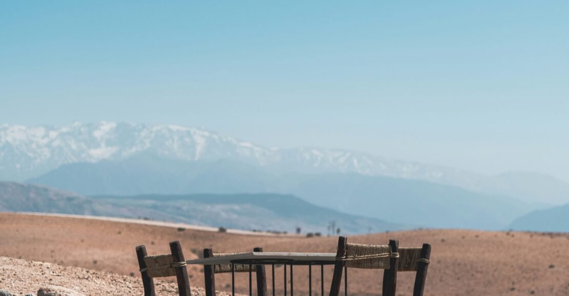 a wooden table and chairs sitting in the middle of a desert